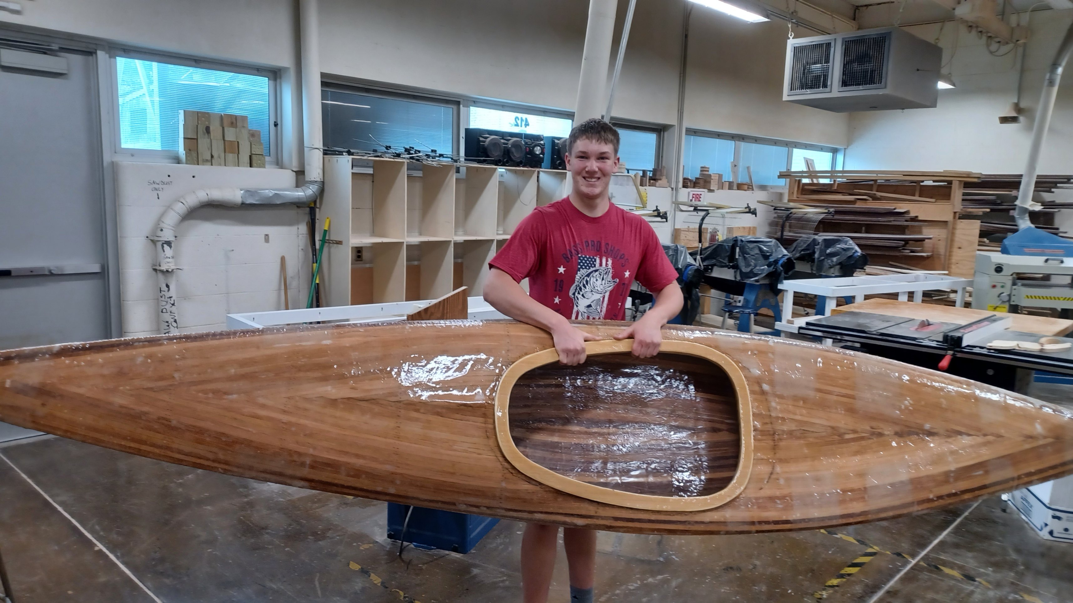 Andrew Kornbau holds the kayak he made in the wood shop.